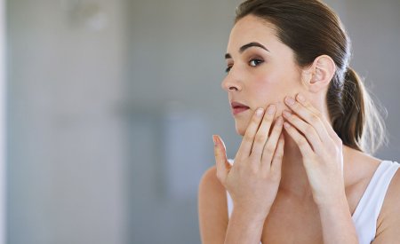 Woman checking her skin in a mirror