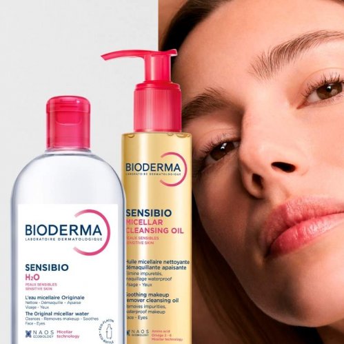 Model with radiant skin beside a bottle of Sensibio H2O Micellar Water and Sensibio Micellar Cleansing Oil